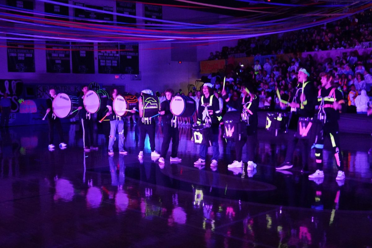 Drum line performing Sharkbait during Santa Fes Double Wolf Dare Week Blacklight assembly. 