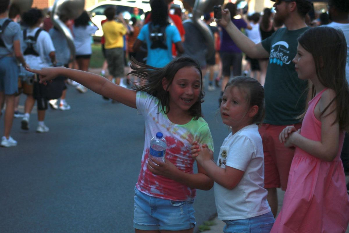 A neighborhood girl excitedly shows off her band sibling. 