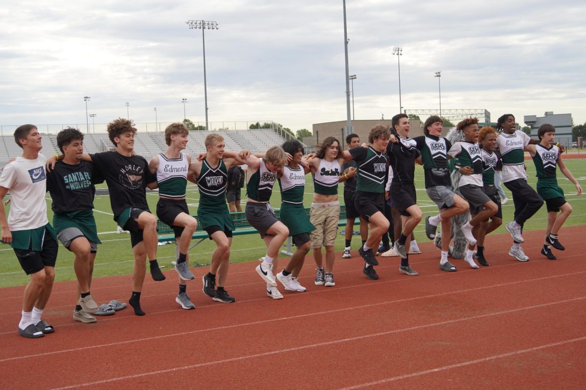 Cheerleaders performing a kick-line for students in the stands. 