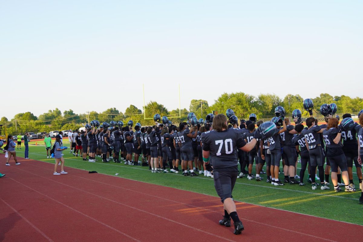 Football team holding up their helmets for kickoff.