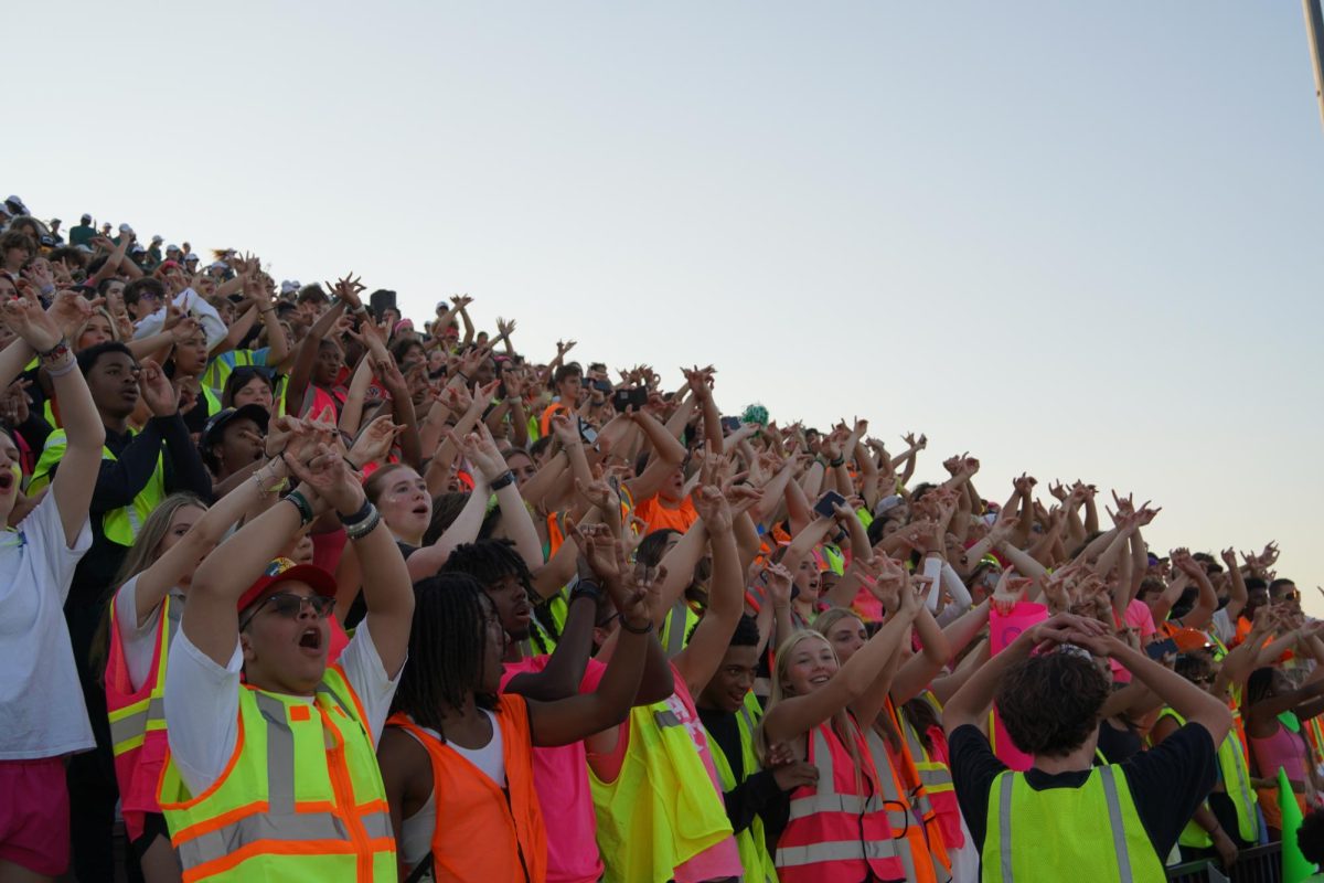 Student section cheering and decked out in neon.