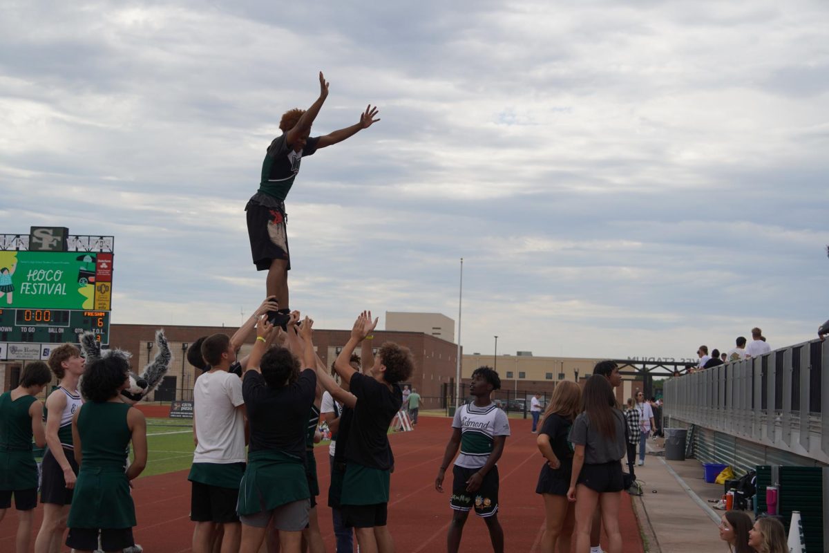 Cheerleaders working together to lift another student.