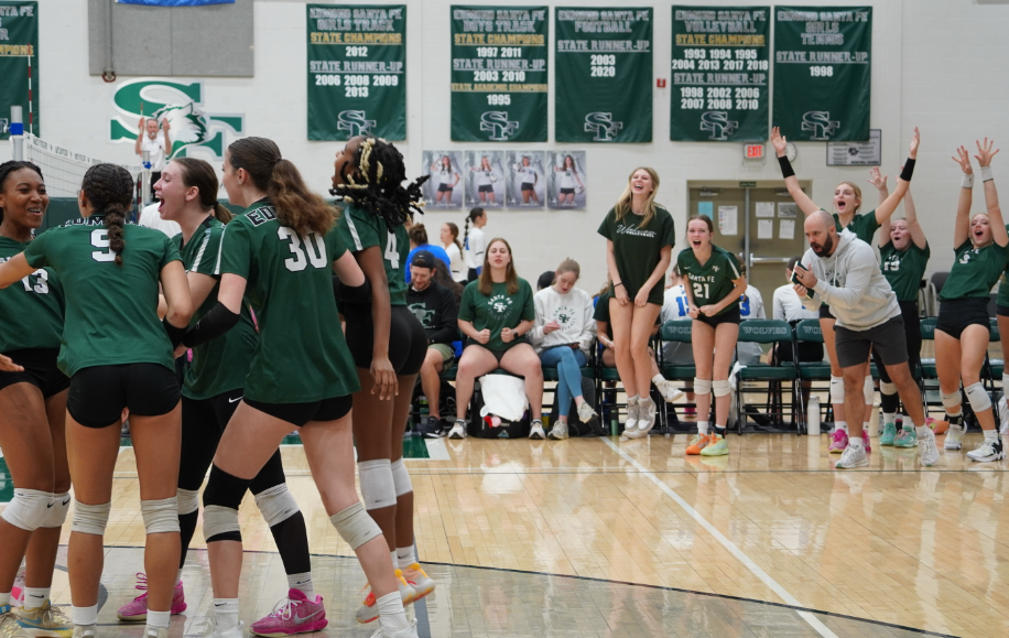 The varsity volleyball team celebrates after Caryl Womack delivers a solid hit, securing a point for the team. 