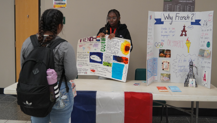 Sophomores Victoria Oke and Tereon Nolan showcase French Club to a fellow student.