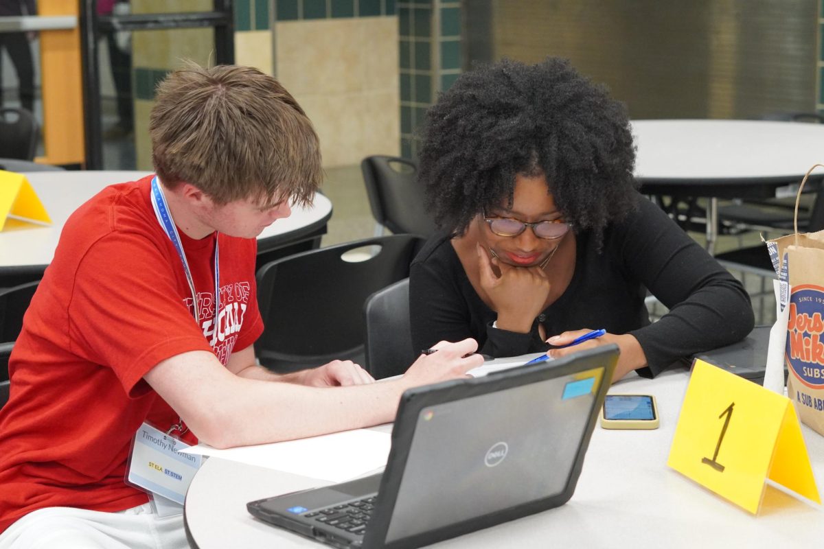 Senior Timothy Newman helps junior Christian Brown during an AASP meeting. 