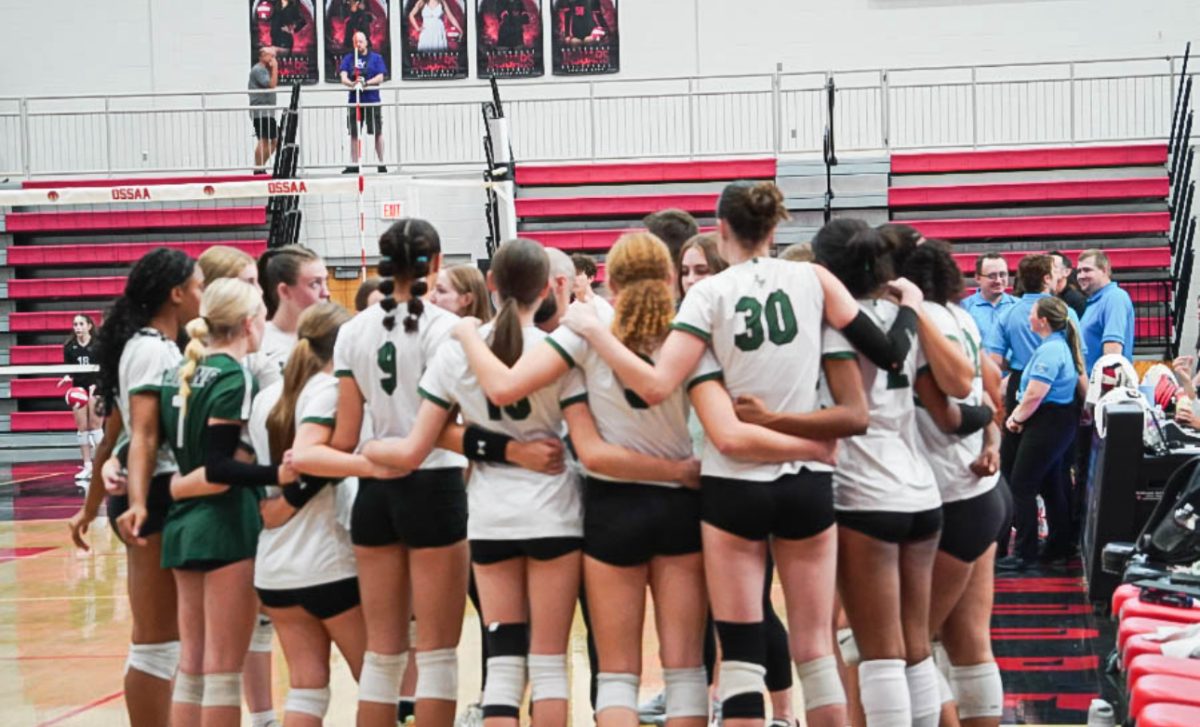 The Santa Fe girls varsity volleyball team stands huddled together moments before the game begins.