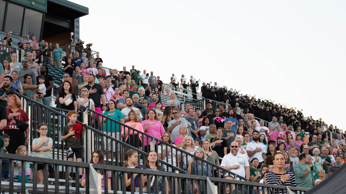 Families of Santa Fe students stand for the Pledge of Allegiance at the football game, where proceeds went toward Spurgeon's treatment costs.