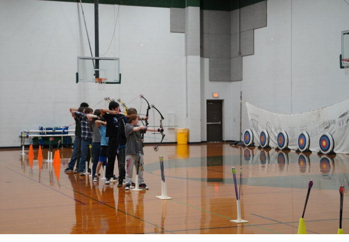 Archery students hold their bows in preparation to hit the targets. 