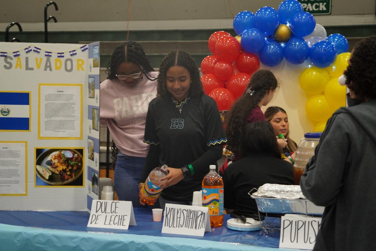 Junior Lydia Molina pouring drinks at the El Salvador booth.