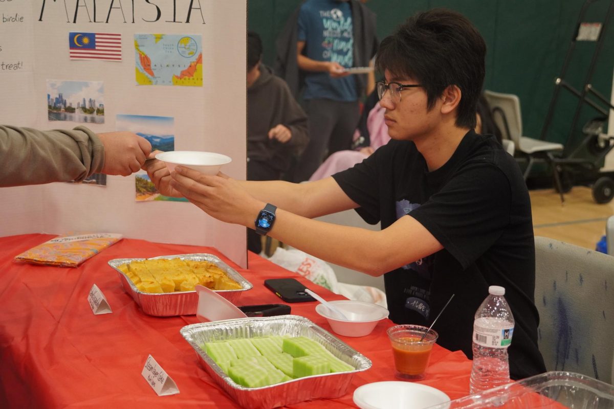 Students serving food at the Malaysian booth. 