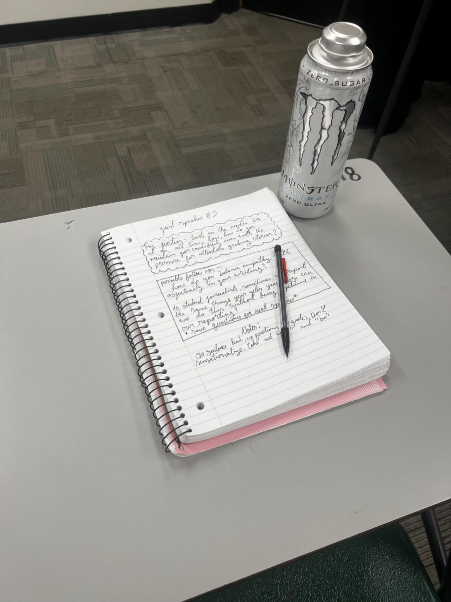 Student's desk with notebook, pencil and Monster energy drink.