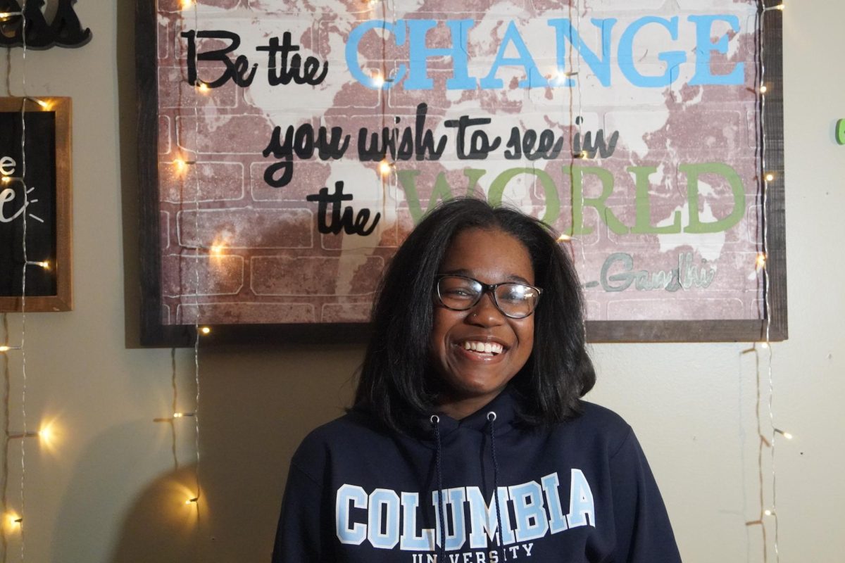 Senior Madison Hayes pictured in front of sign that reads "be the change you wish to see in the world."