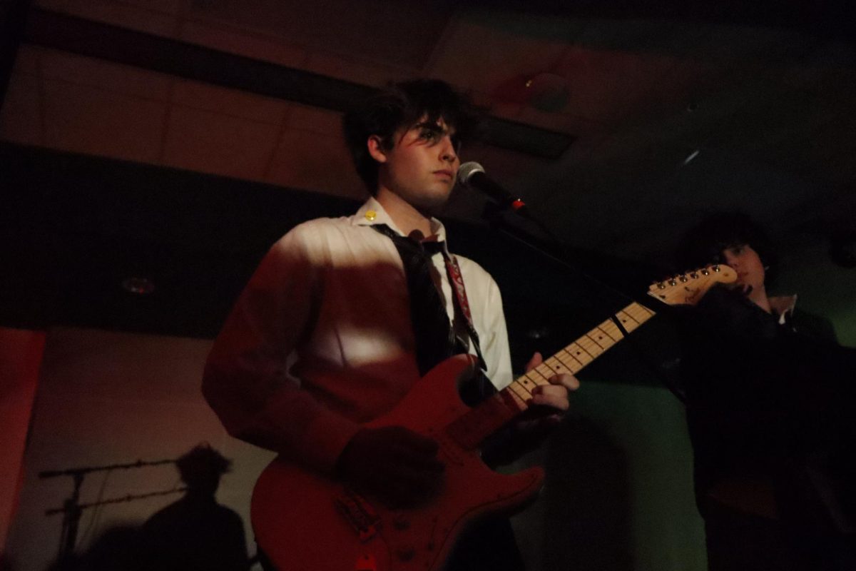 Edmond North senior Emerson Wyrick playing guitar with sophomore Luka Grice.