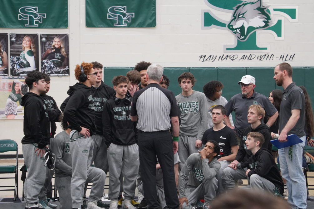 The Santa Fe boys' wrestling team gathers together to listen to referee.