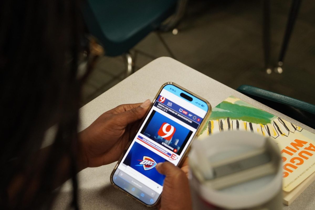Junior Aniyah Calhoun holding her phone and looking at the News 9 website. 