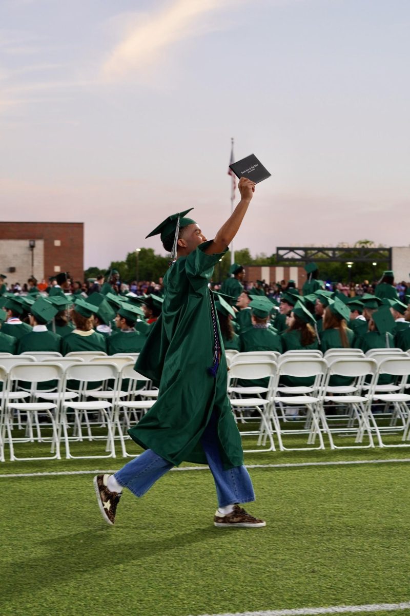 A senior showing his diploma off to the crowd at the class of 2025 graduation.