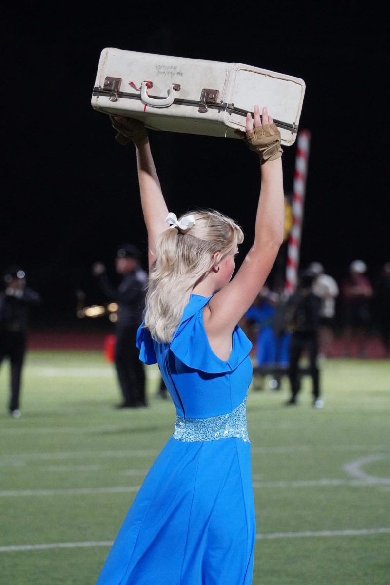 Color guard member Kyleigh Goodyear holding up a suitcase. 