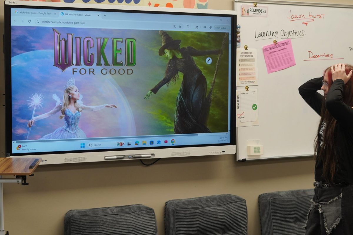 Junior Ava King looking at Wicked: For Good movie cover. 