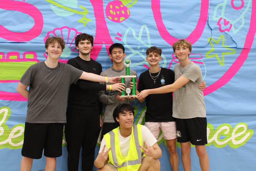 The team "Mission Unblockable" posing with their trophy after winning the blacklight volleyball tournament.