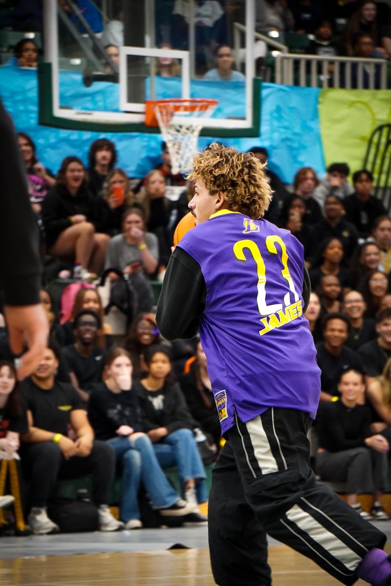Junior Eli Fina getting ready to dunk a basketball during Boy Bands assembly.