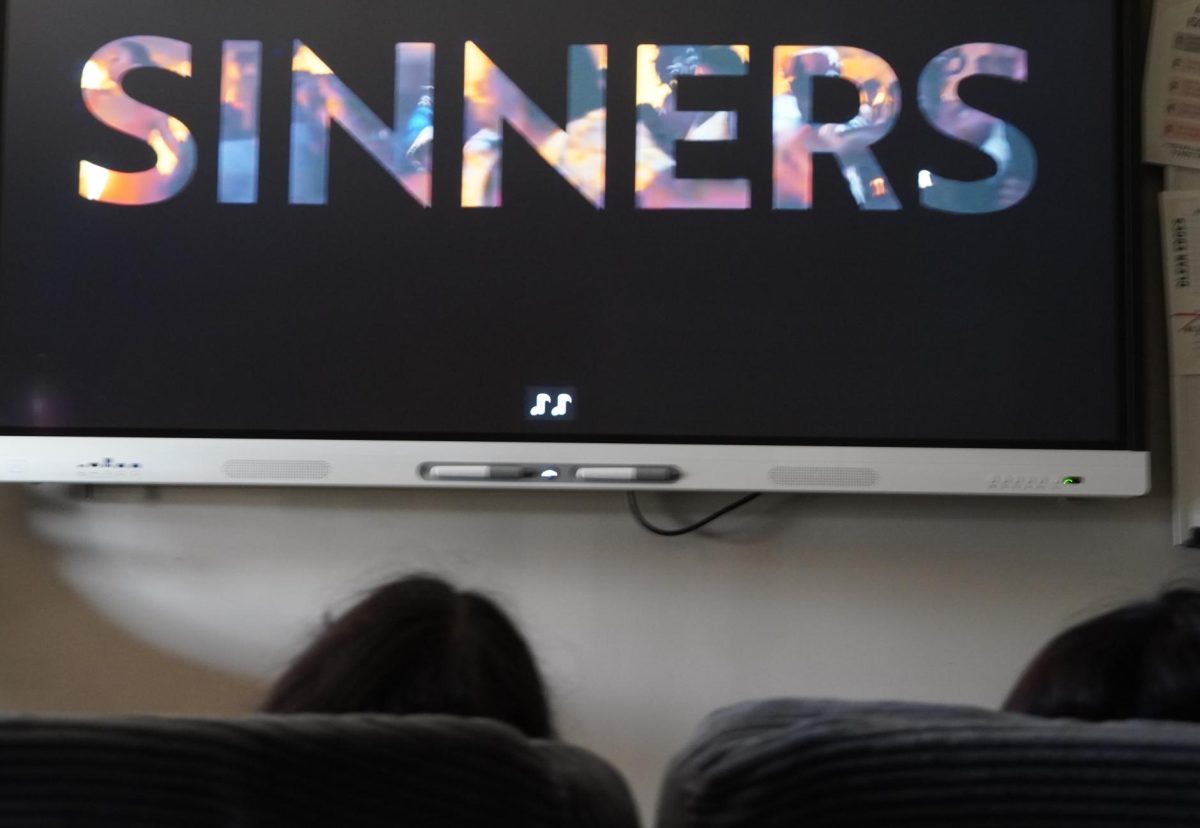 Two students engaged while watching a SInners movie trailer.