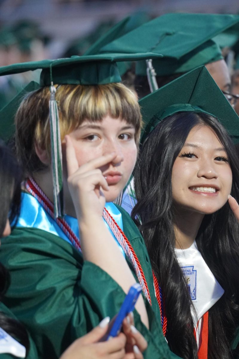 Seniors Karla Le and Tristan Haley posing with a peace signs during the graduation ceremony 