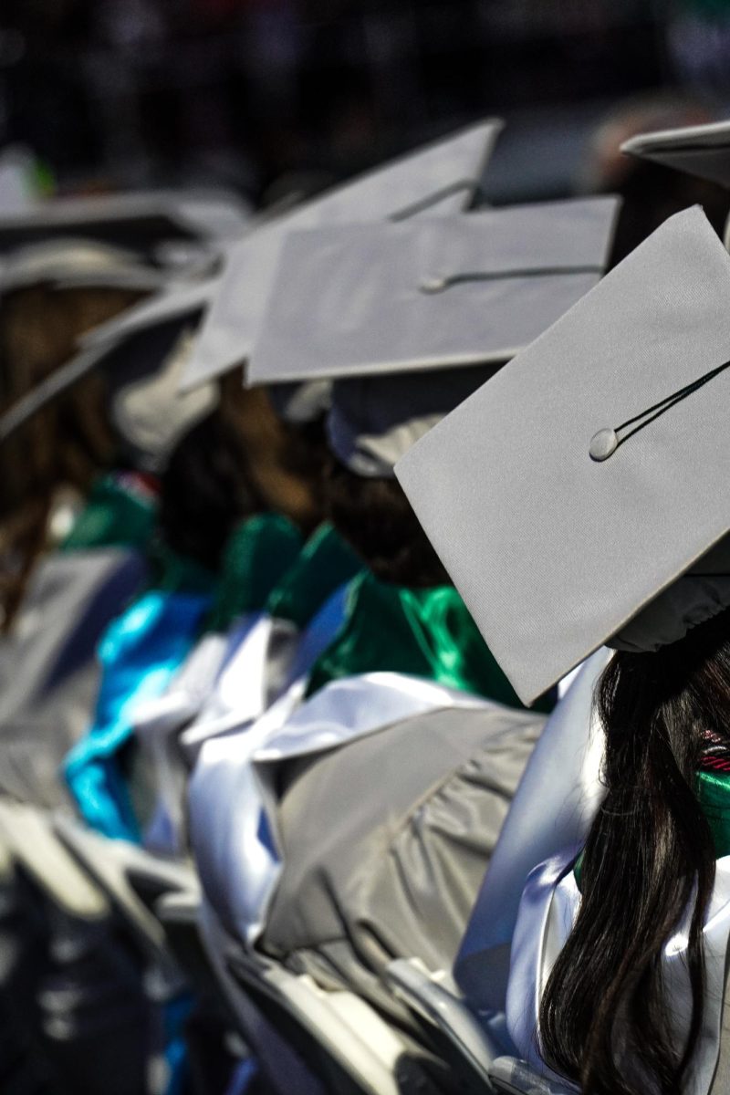 Senior valedictorians sitting down looking away from the camera during graduation. 