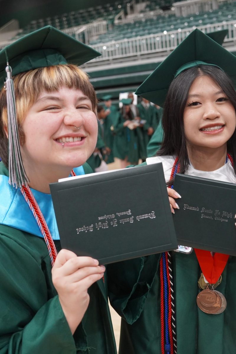 Seniors Tristan Haley and Karla Le smiling and posing with their high school diplomas. 